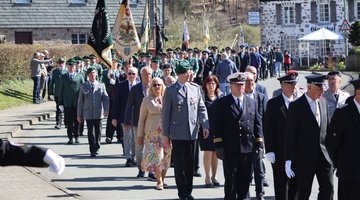 Das Foto zeigt den Festumzug zum Ehrenmal in Sundern-Hellefeld. Neben den Schützen, Reservisten und anderen, lokalen Vereinen mit jeweiligem Banner erkennt man in der Bildmitte auch den Kreisvorsitzenden des Volksbundes im Hochsauerland, Hubert Kleff, sowie den Bezirksvorsitzenden, Regierungspräsident Heinrich Böckelühr.
